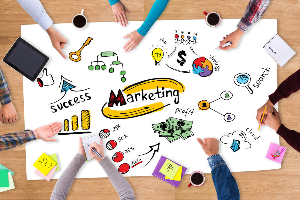 A group of people leaning over a table preparing their marketing campaign