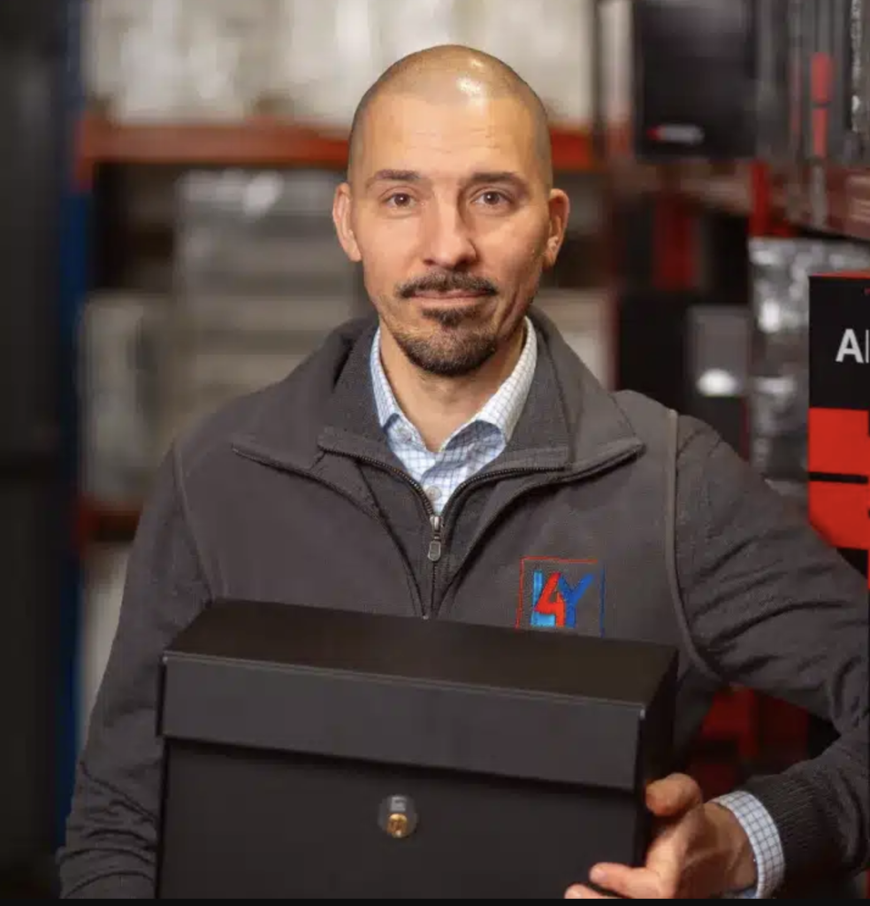 Photo of Dominic Poznanski, founder of Letterbox4you, holding a post box in a warehouse environment