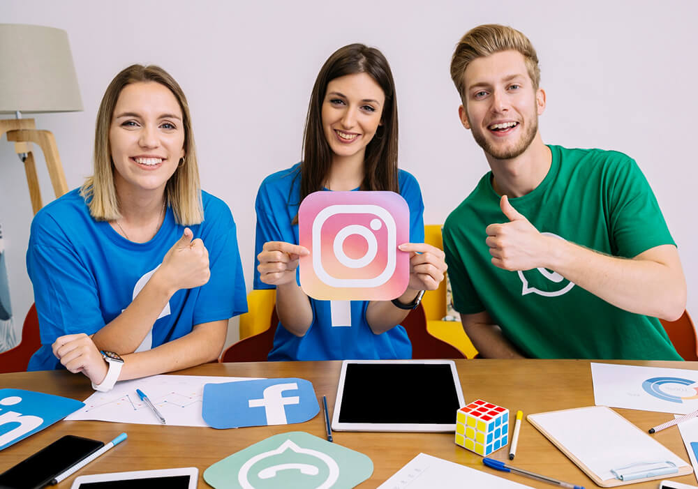 A woman holding up the Instagram logo while a man and another woman cheer her on from either side.