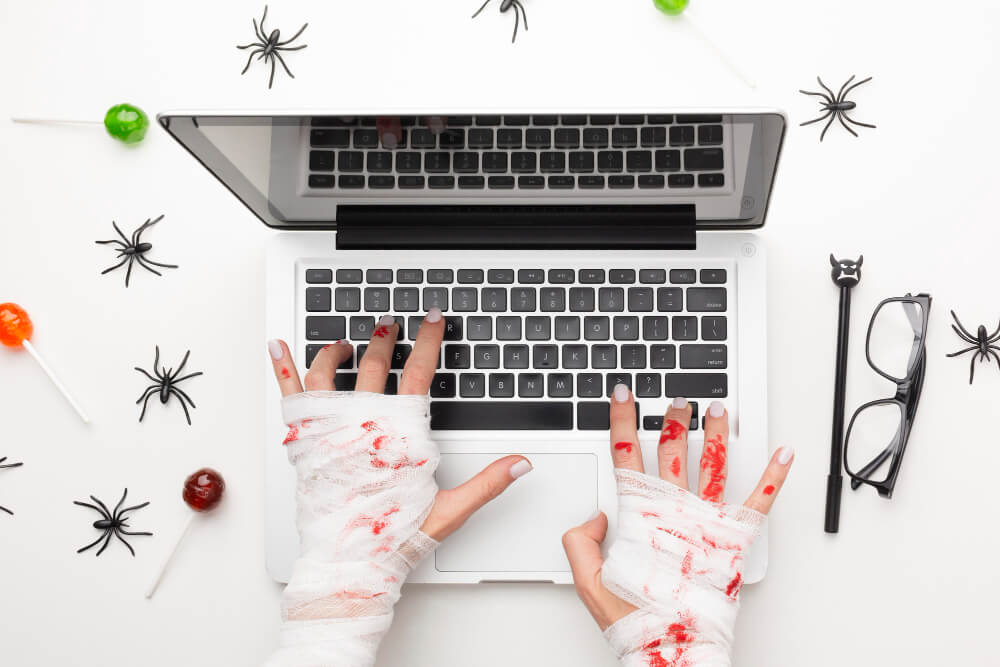 Bandage, bloody hands using the keyboard of a laptop, with spiders surrounding the laptop